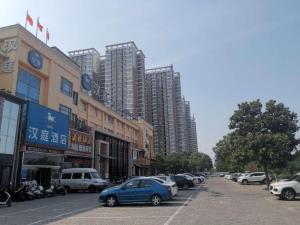 a blue car parked on a street with tall buildings at Hanting Hotel Luoyang Municipal Government in Guanlin