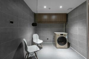 a laundry room with two white chairs and a washing machine at Hanting Hotel Wuzhong Wanda Plaza in Wuzhong