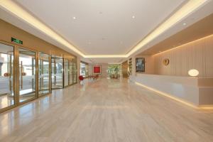 a large hallway with a large room with wooden floors and windows at Ji Hotel Daxing Biomedical Base Hotel in Daxing