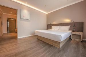 sypialnia z dużym białym łóżkiem i drewnianą podłogą w obiekcie Hanting Hotel Shenyang Nanta Shoe Market w mieście Shenyang