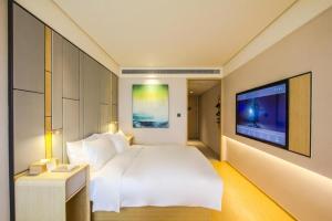 1 dormitorio con 1 cama blanca y TV de pantalla plana en Ji Hotel Hangzhou Linping Xincheng, en Yuhang