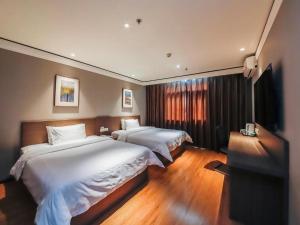 a hotel room with two beds and a flat screen tv at Hanting Hotel Zhengzhou Technology Market in Zhengzhou