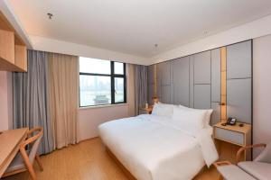 a bedroom with a large white bed and a desk at Ji Hotel Nanchang Tengwang Pavilion in Nanchang