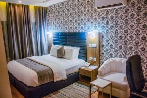 une chambre d'hôtel avec un lit et une chaise dans l'établissement Crownsville Hotel - Airport Road, à Port Harcourt