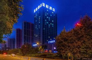 西寧的住宿－Starway Hotel Xining Chengbei Wanda Plaza，一座高大的建筑,晚上有蓝色的灯光