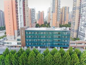 een groot blauw gebouw in een stad met hoge gebouwen bij Ji Hotel Jinan East Railway Station in Licheng