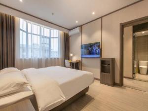 una camera da letto con un grande letto bianco e una televisione di Hanting Hotel Zhijiang Yanjiang Avenue a Zhijiang