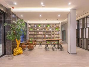 sala de estar con mesa, sillas y biblioteca en Hanting Hotel Zhijiang Yanjiang Avenue, en Zhijiang