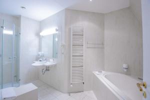 a white bathroom with a tub and a sink and a shower at Seehotel Brandenburg an der Havel in Brielow +83 photos