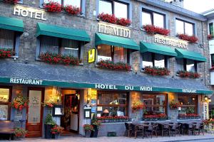 a hotel with tables and chairs in front of a building at Logis Hotel Du Midi in La Roche-en-Ardenne