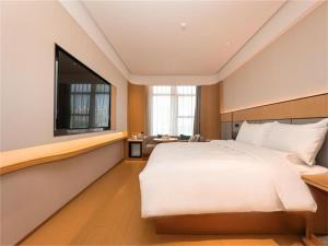 Ji Hotel Nanjing Baijia Lake في Jiangning: غرفة نوم بسرير كبير ونافذة كبيرة