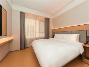 Ji Hotel Nanjing Baijia Lake في Jiangning: غرفة نوم بسرير ابيض كبير ونافذة