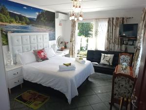 - une chambre avec un grand lit blanc et un canapé dans l'établissement Queensburgh B&B or Self Catering, à Durban