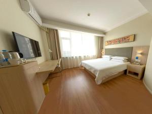 una camera d'albergo con letto e TV di Hanting Hotel Jilin Jiangbei Park a Jilin