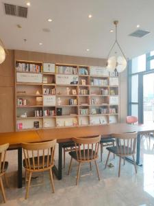 a dining room with a table and chairs and bookshelves at Hanting Hotel Nanyang Railway Station in Nanyang