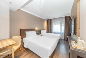 Hanting Hotel Shanghai Huaihai Zhong Road Metro Station tesisinde bir odada yatak veya yataklar