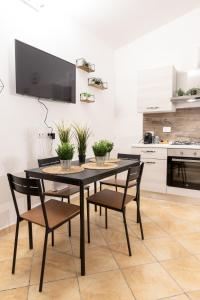 mesa de comedor negra con sillas y TV en la pared en Suite Gli Ulivi, en Colonna