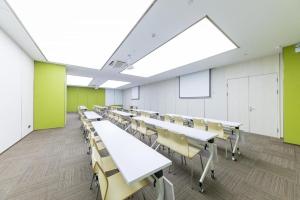 a classroom with white tables and chairs and green walls at Ji Hotel Heze Renmin Road in Heze