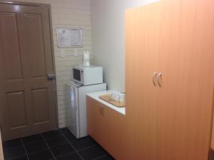a small kitchen with a refrigerator and a microwave at Budget Motel in Midland Junction +11 photos