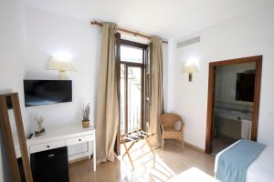 um quarto com uma cama, uma secretária e uma janela em Hotel San Miguel em Córdoba