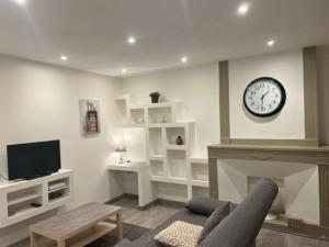 a living room with a fireplace and a clock on the wall at Le studio du centre in Montélimar