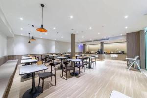 a restaurant with tables and chairs and a counter at Hanting Hotel Taicang Wanda Plaza in Taicang