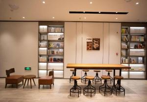 a library with a table and chairs and bookshelves at Hanting Hotel Hunchun Railway Station in Hunchun