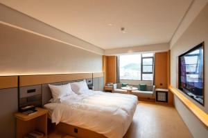 - une chambre avec un grand lit et une télévision dans l'établissement Ji Hotel Guilin Two Rivers And Four Lakes Scenic, à Guilin