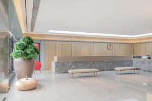 a lobby with a plant in a pot and benches at Ji Hotel Tianjin Cultural Center in Yutai