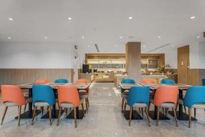 a cafeteria with tables and chairs and a kitchen at Hanting Premium Hotel Yantai Development Zone Golden Beach in Fushan