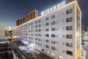 un hotel blanco con un cartel en el costado en Hanting Premium Hotel Yantai Development Zone Golden Beach, en Fushan