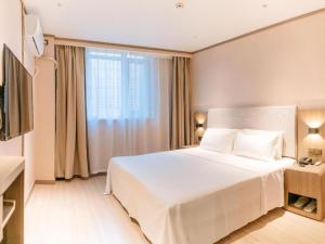 a bedroom with a large white bed and a window at Hanting Hotel Taiyuan Qianfeng South Road in Xiayuan