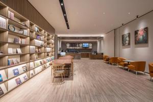 a library with chairs and tables and bookshelves at Hanting Hotel Nantong Railway Station in Nantong