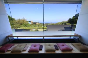 a room with four beds in front of a large window at Yutorelo Atami in Atami