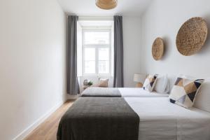 zwei Betten in einem weißen Zimmer mit Fenster in der Unterkunft Rua Augusta Dream Apartment in Lissabon