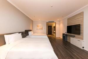 a hotel room with two beds and a flat screen tv at Hanting Premium Hotel Xining Tangdao Wanda Plaza in Xining