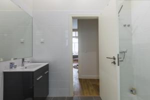 ein weißes Badezimmer mit Waschbecken und Spiegel in der Unterkunft Rua Augusta Dream Apartment in Lissabon + 34 Fotos