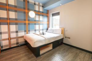a small bed in a room with a striped wall at easyHotel Glasgow City in Glasgow