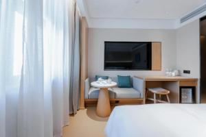 a hotel room with a bed and a table and a tv at Ji Hotel Fuzhou Wuyi Square in Fuzhou