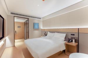 a bedroom with a large white bed and a television at Ji Hotel Wenzhou Feixia South Road in Wenzhou