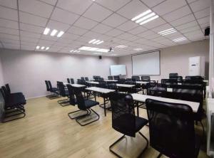 una sala con mesas y sillas en un aula en Hanting Hotel Qingdao Wanxiang City, en Qingdao