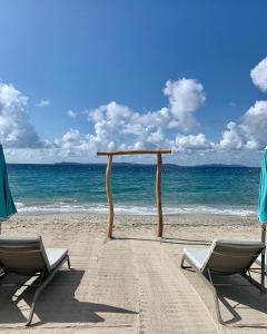 an arch on a beach with two chairs and the ocean at Hôtel La Villa Douce in Rayol-Canadel-sur-Mer