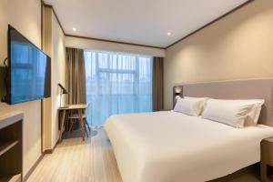 a bedroom with a large white bed and a desk at Hanting Hotel Hangzhou Zhejiang University Of Technology in Hangzhou