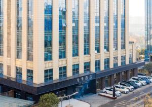 an office building with cars parked in a parking lot at Ji Hotel Guiyang Guanshan Lake High-Tech Zone in Jinzhuzhen