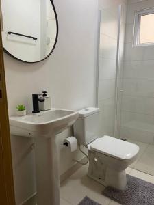 ein Badezimmer mit einem Waschbecken, einem WC und einem Spiegel in der Unterkunft Apartamento próximo a uopeccan in Umuarama