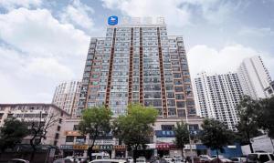 a large building with a sign on top of it at Hanting Hotel Xinyang Railway Station in Xinyang