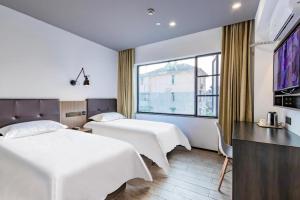 Habitación de hotel con 2 camas y ventana grande. en Hi Inn Hangzhou Sijiqing Qiutao North Road, en Hangzhou