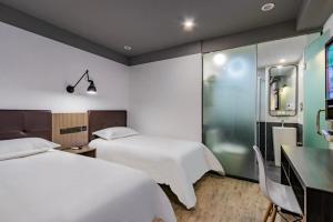 a hotel room with two beds and a desk and a table and chairs at Hi Inn Hangzhou Sijiqing Qiutao North Road in Hangzhou