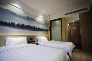 two beds in a hotel room with a painting on the wall at Hanting Hotel Chuzhou Dingyuan Shopping Building in Dingyuan