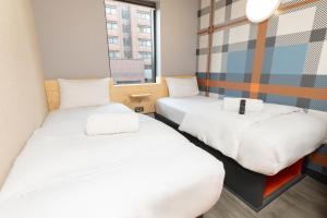two beds in a small room with a window at easyHotel Glasgow City in Glasgow